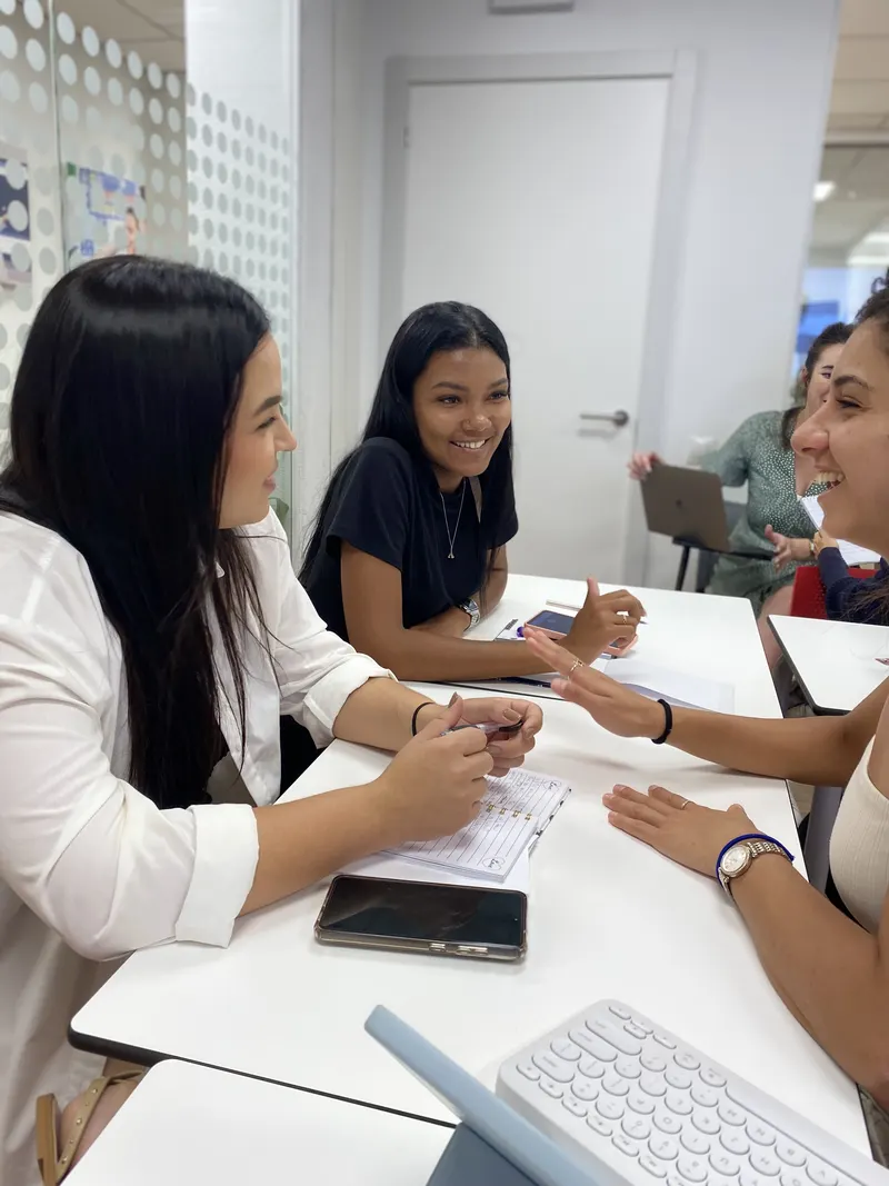 Alumnas practicando inglés por parejas y riendo durante una clase de conversación