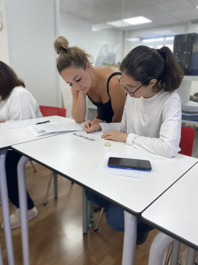 Una profesora en prácticas trabaja de forma individual con una alumna sobre una hoja de ejercicios